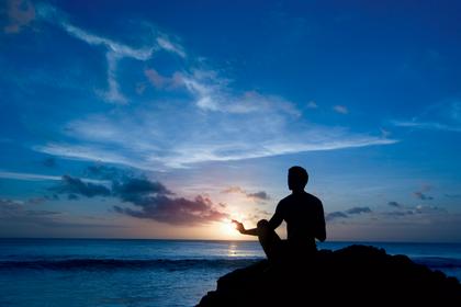 Meditation on rock at ocean at sunset